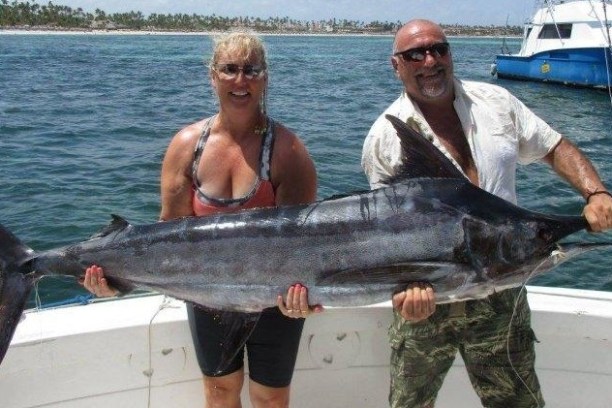 a man holding a fish on a boat in the water